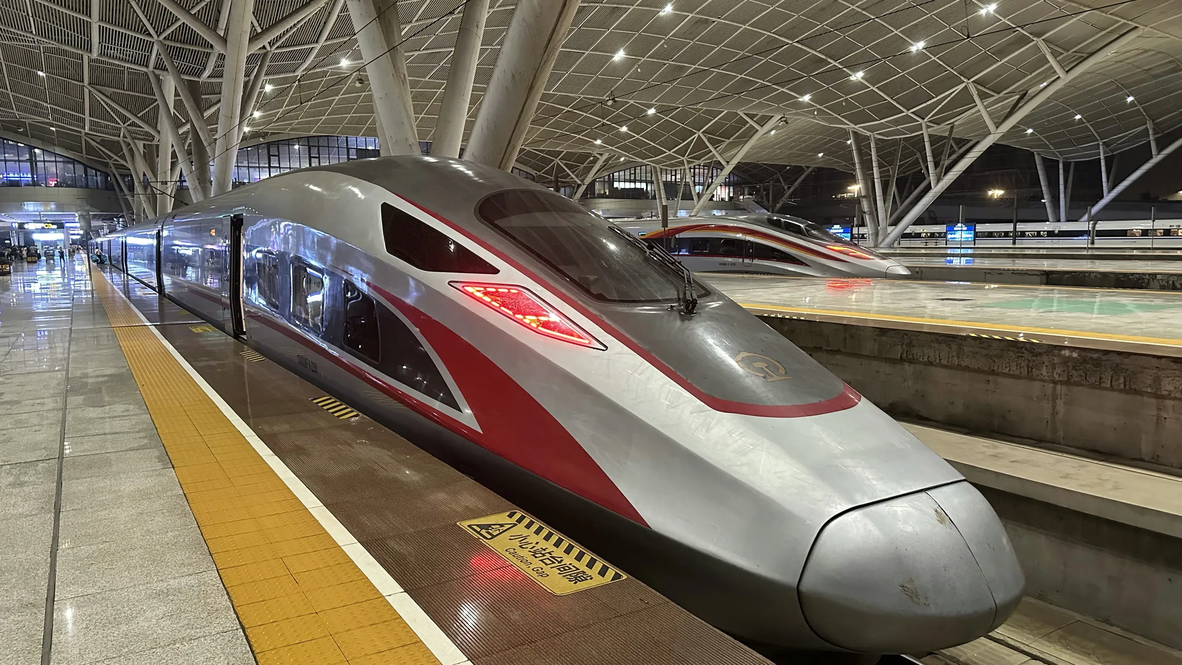 A silver and red high-speed train waiting at the platform